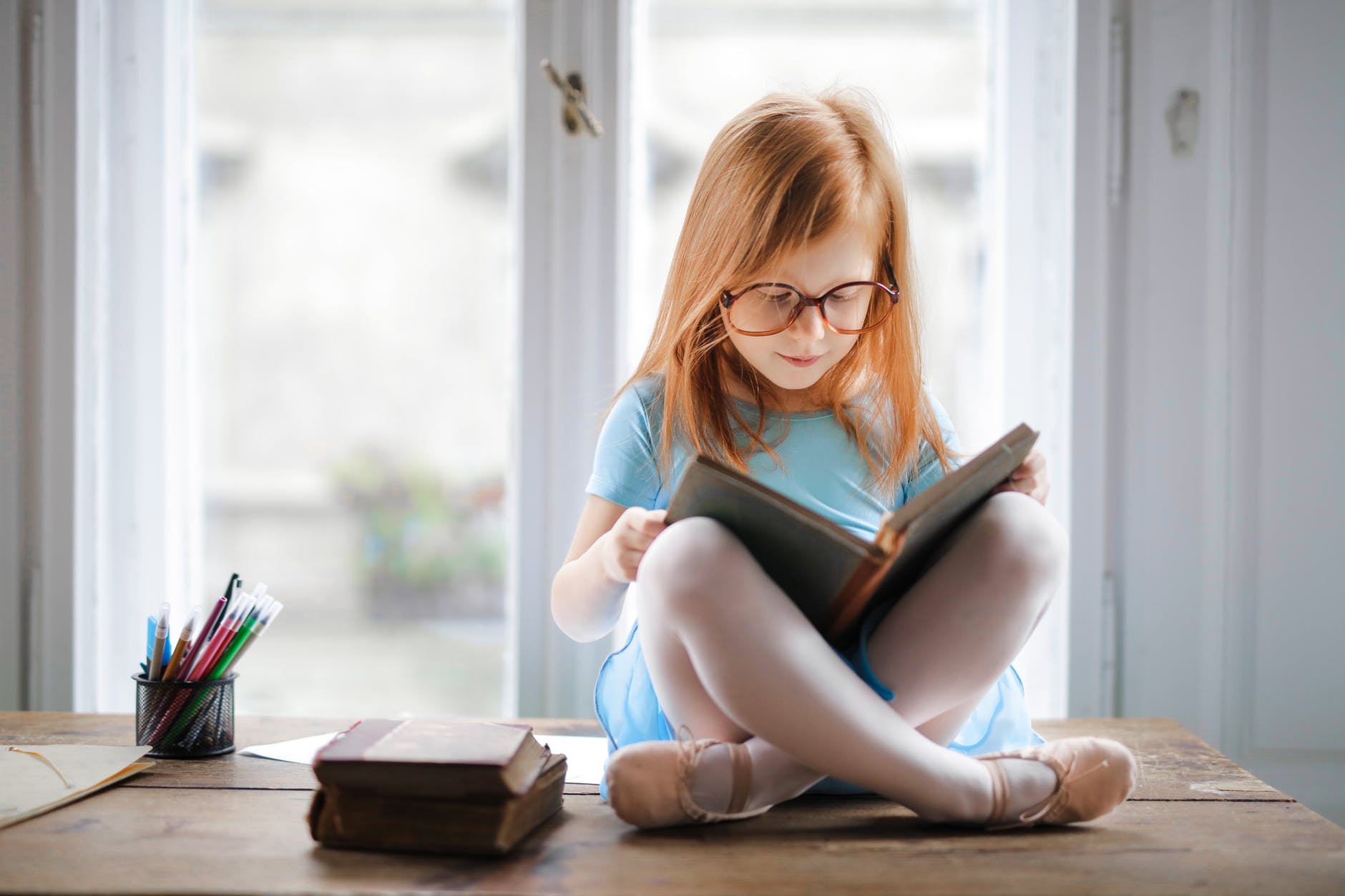 photo of young girl with red hair readng a book
